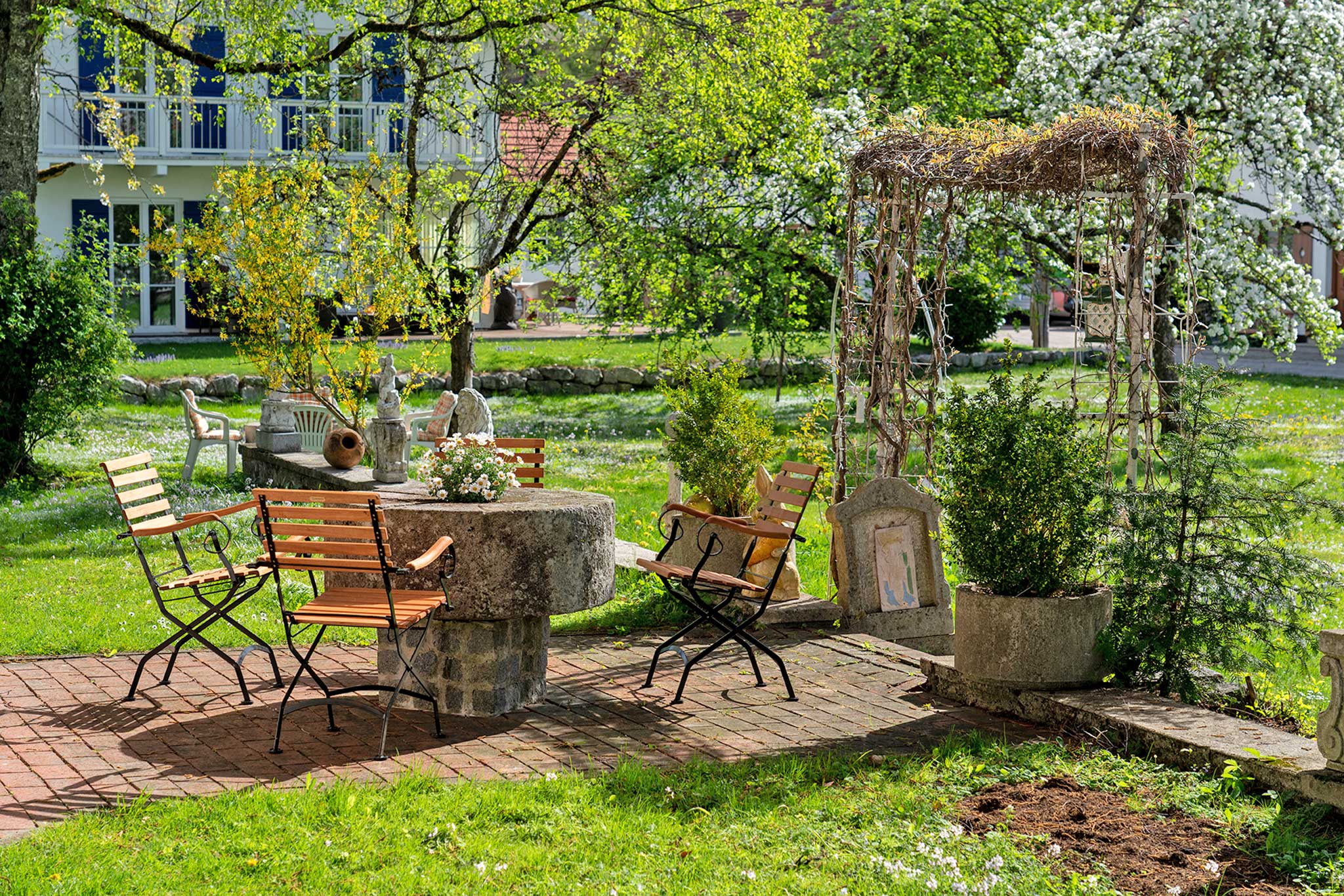 Gaestehaus Heiss Lenggries Garten mit Sitzgelegenheiten Fruehling